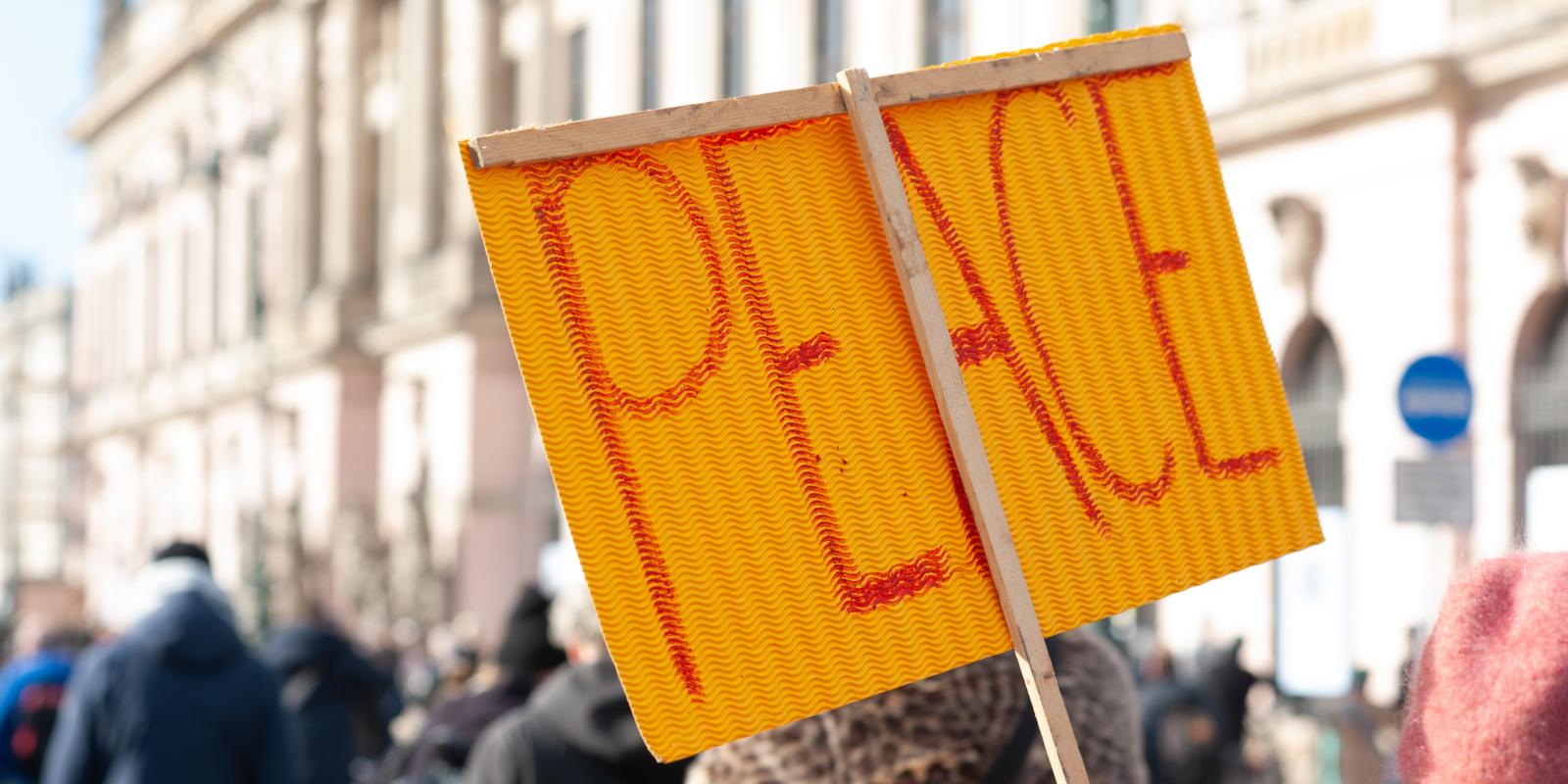 Peace written on a sign held up in a crowd