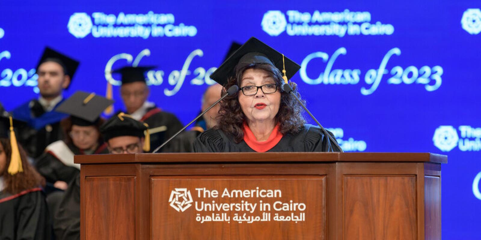 Abdel-Motaal speaks at a podium during commencement while wearing a cap and gown