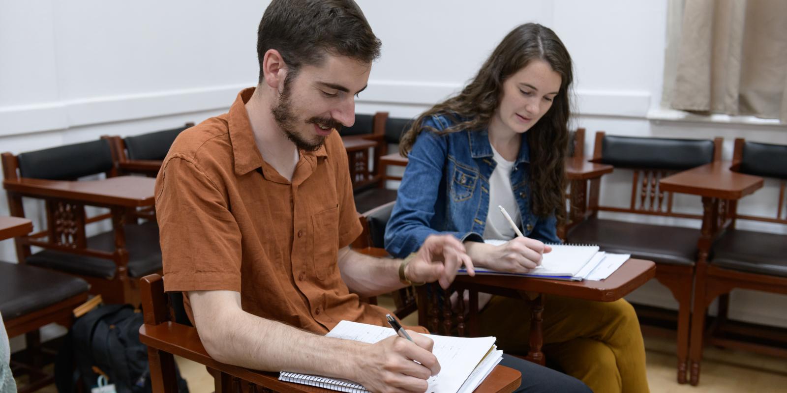 Boy and girl sitting in class writing