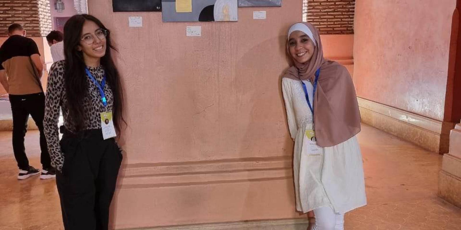Two girls standing beside a wall with their project