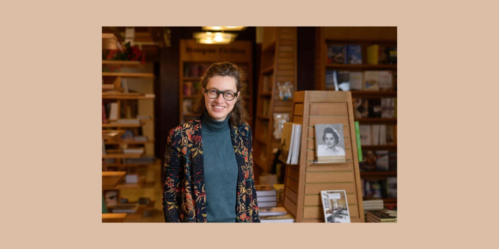 Photo of Veerle De Laet standing and smiling next to book shelves