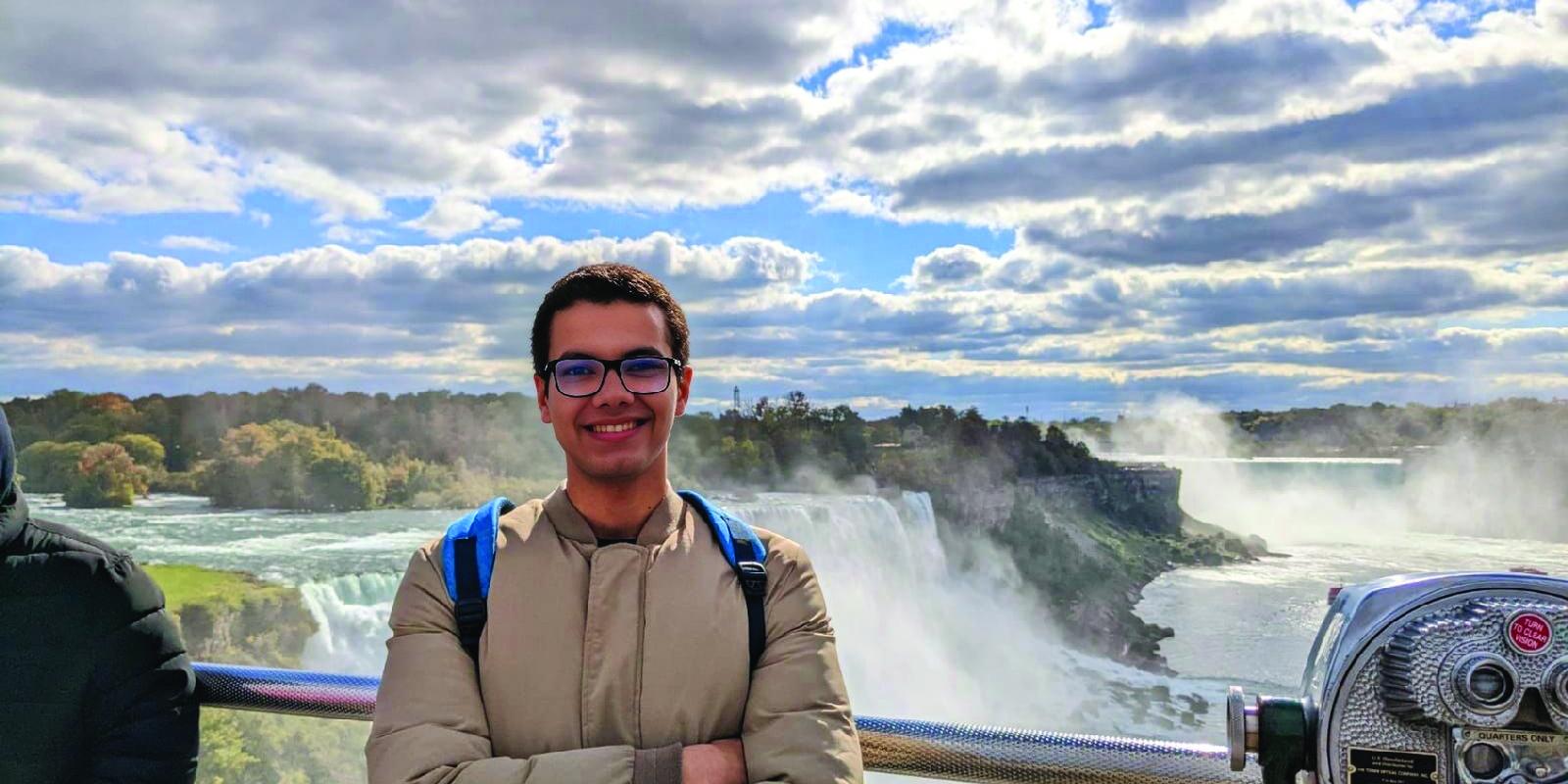 Male student standing in front of a waterfall