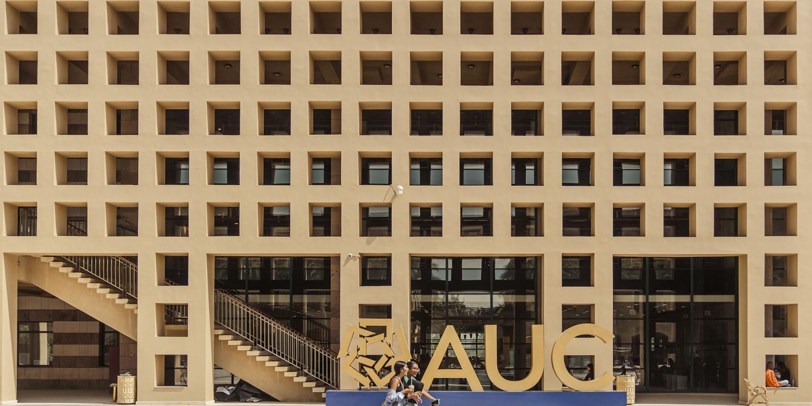 Beige building with hollow squares and a AUC sign in gold 