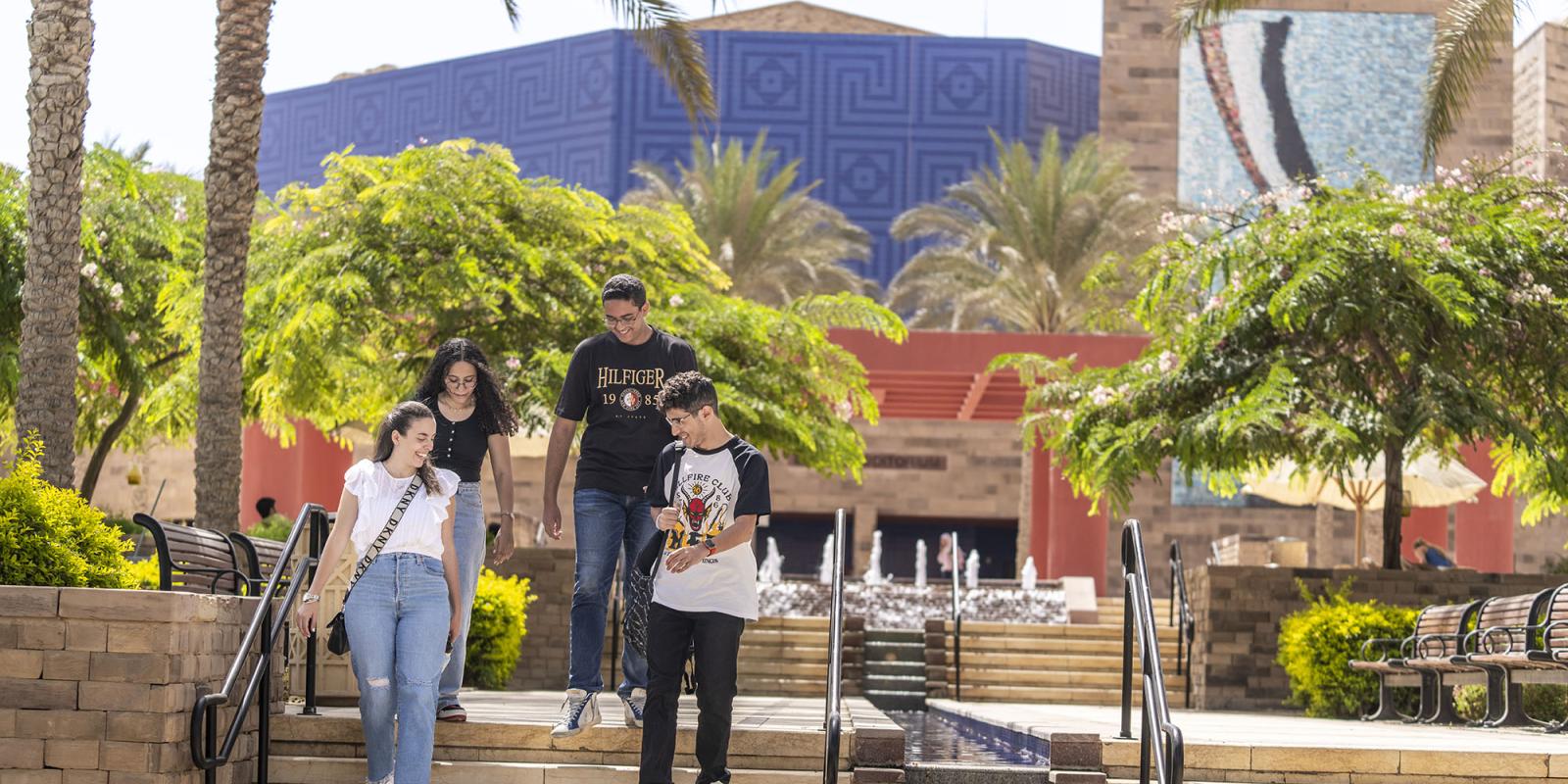 Girls and boys going down the stairs beside a fountain smiling