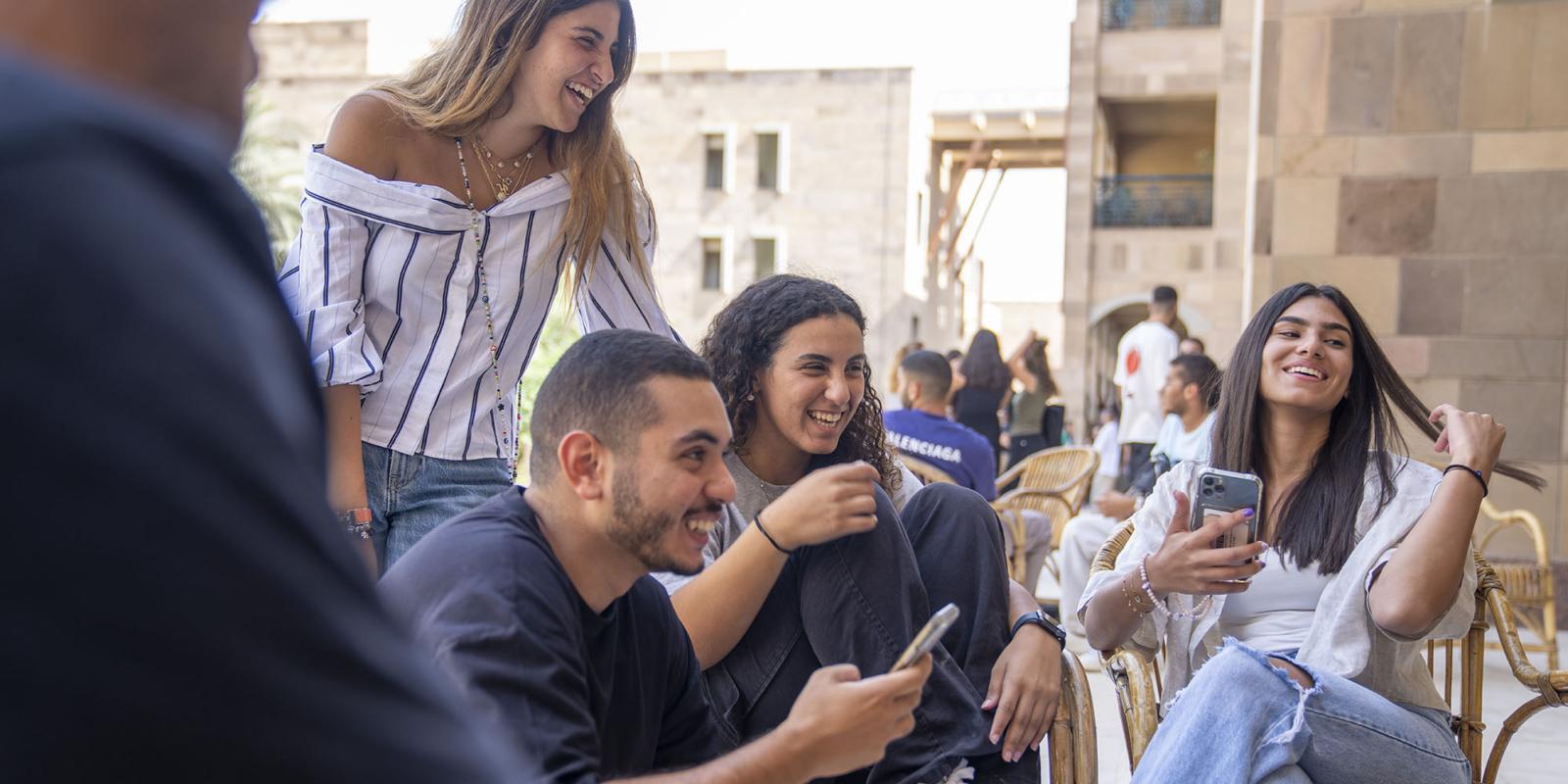 A group of boys and girls sitting on chairs outdoors laughing together