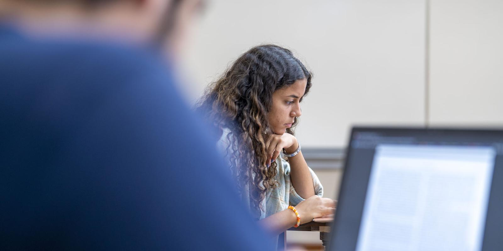 A girl in class sitting on a desk concentrating