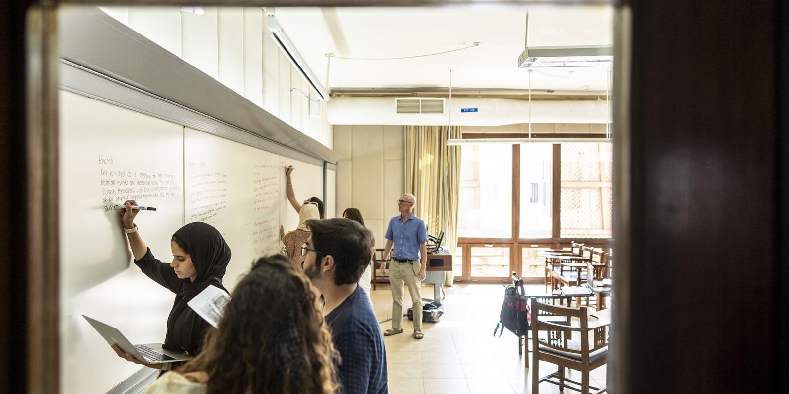 A group of students writing on white board in a classroom