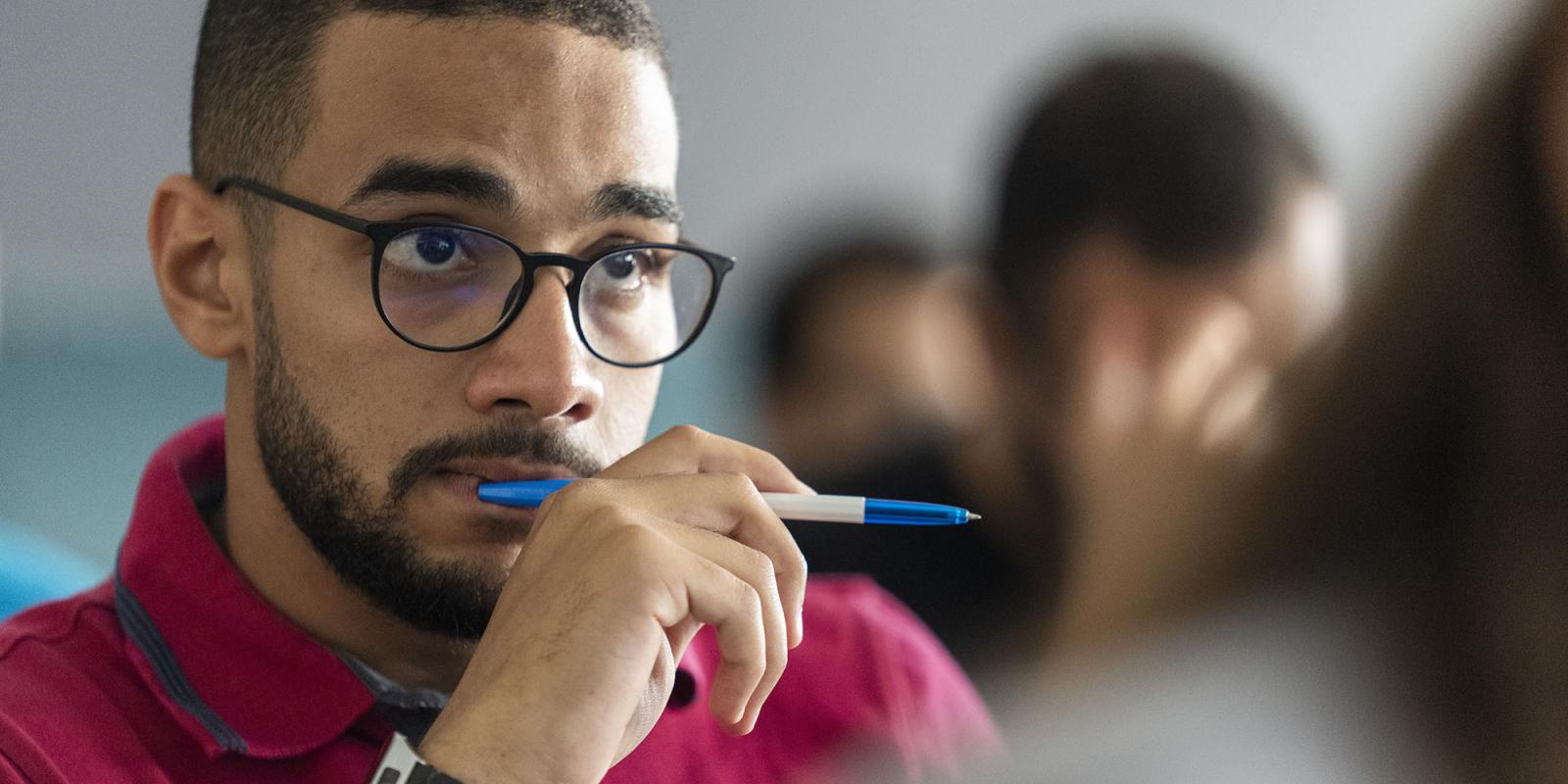 Boy in class wearing glasses and thinking