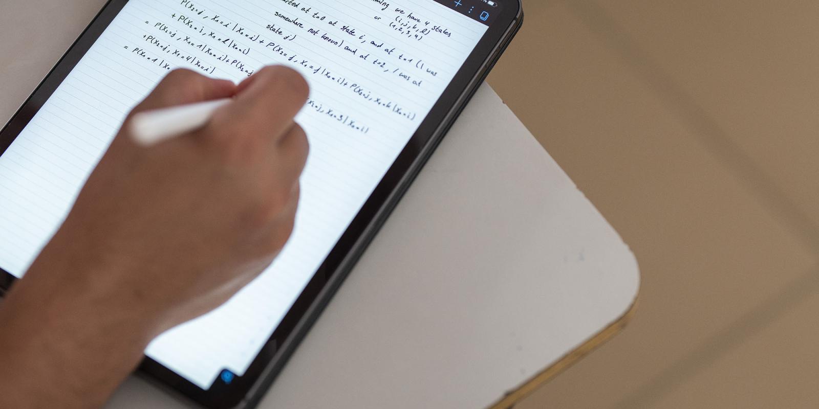 Student hand writing on a tablet