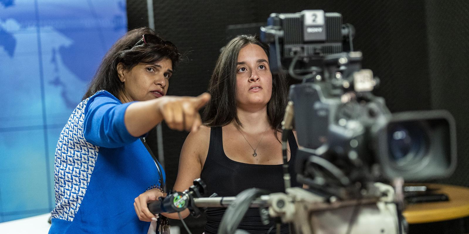 Two women standing behind a camera in preparation to start filming