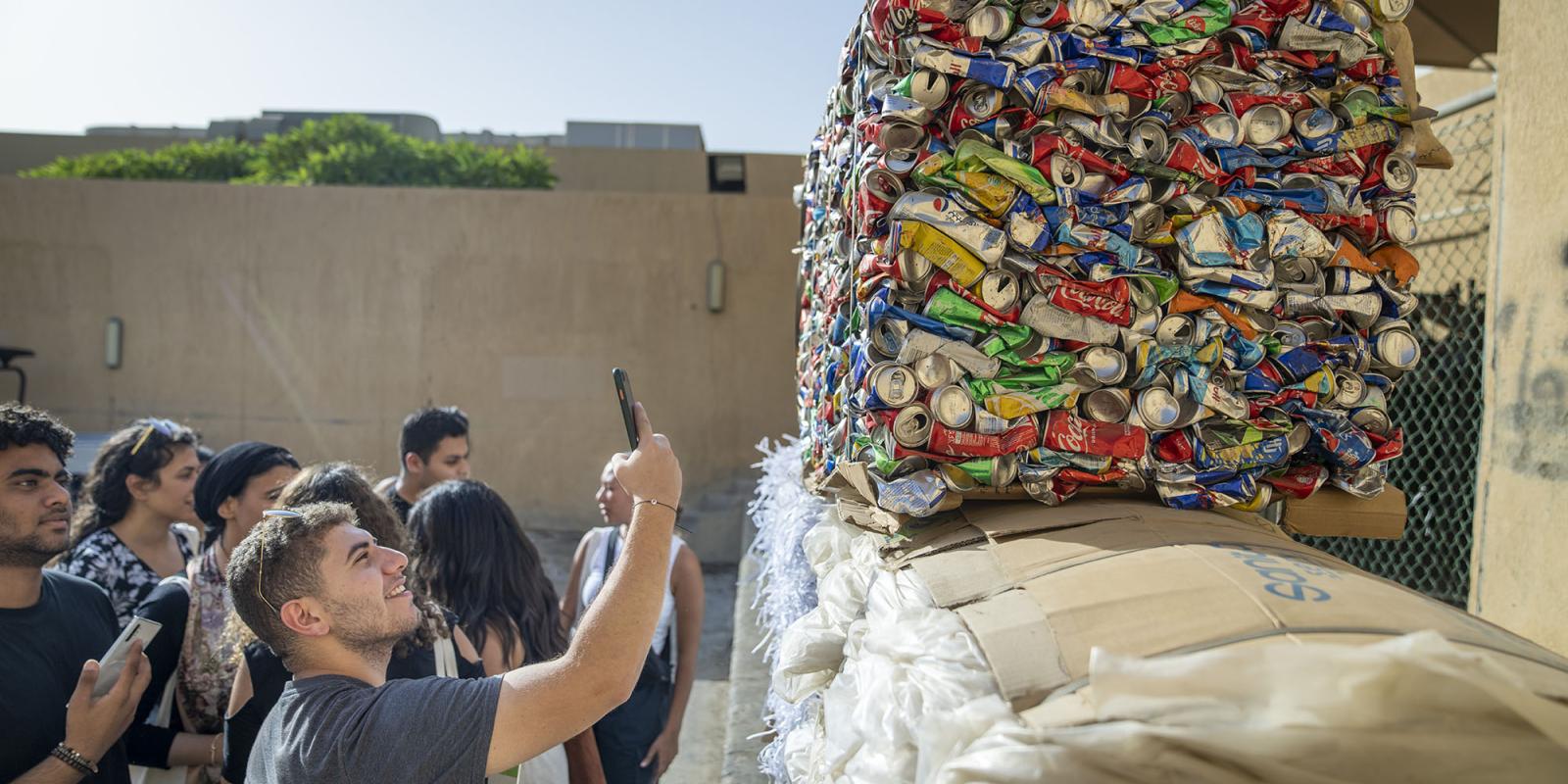 Male student taking a photo of recycled cans