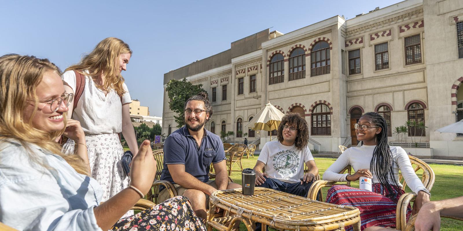 A group of international students sitting around a table in a garden 