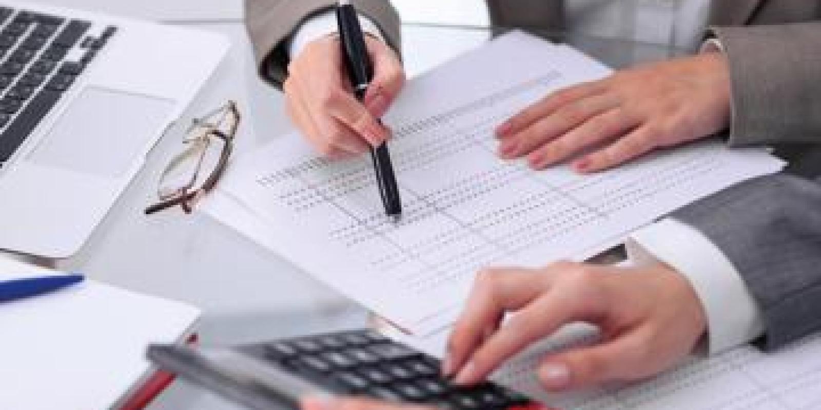Man wearing a suit writing on a white paper
