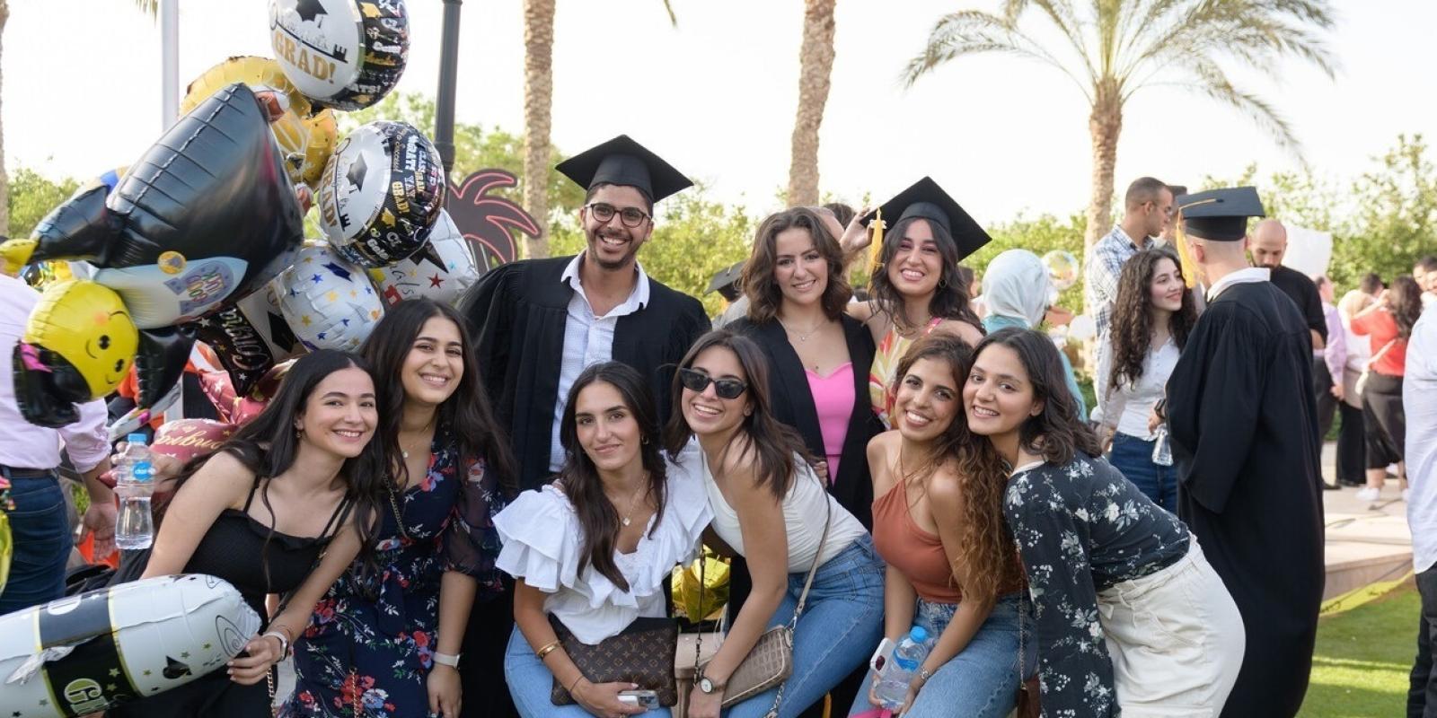 Group of students wearing their caps and gowns and their friends