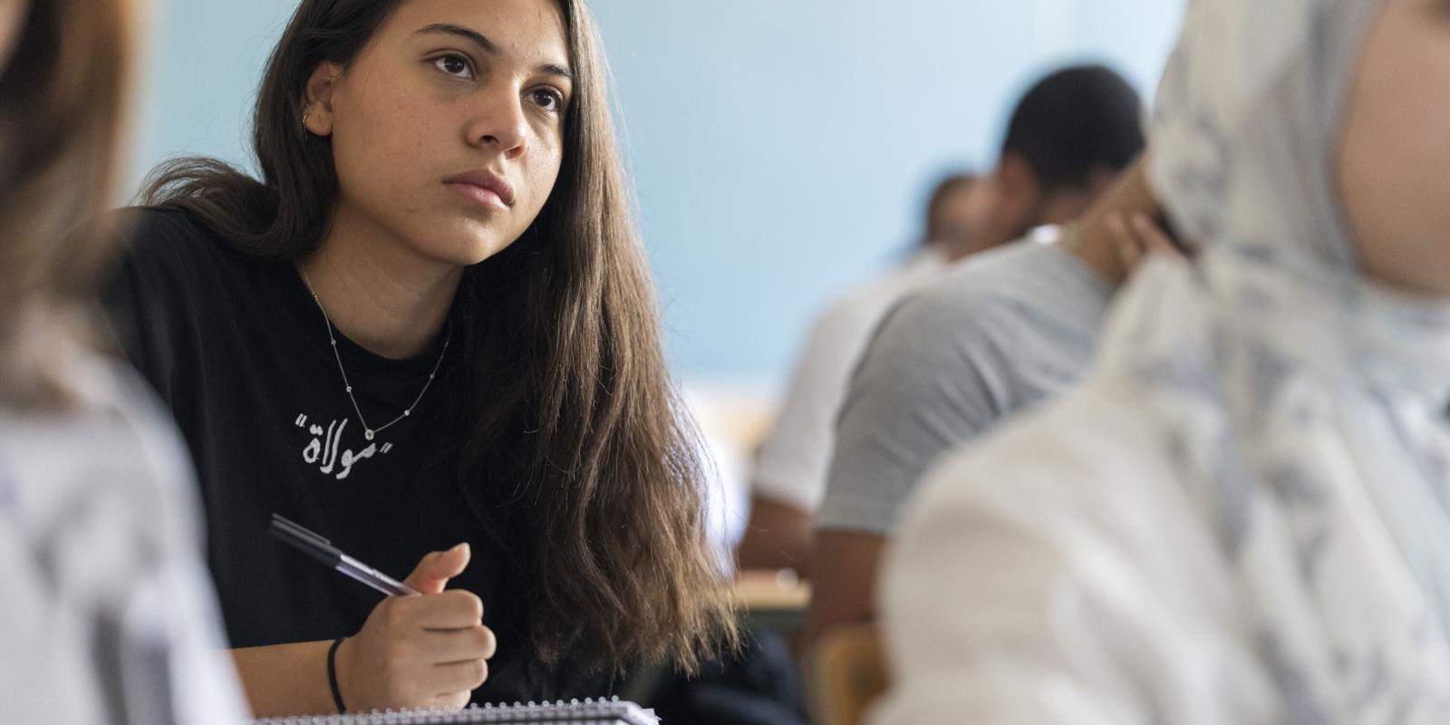 Gender and women studies program image of female student writing notes with her pen in class