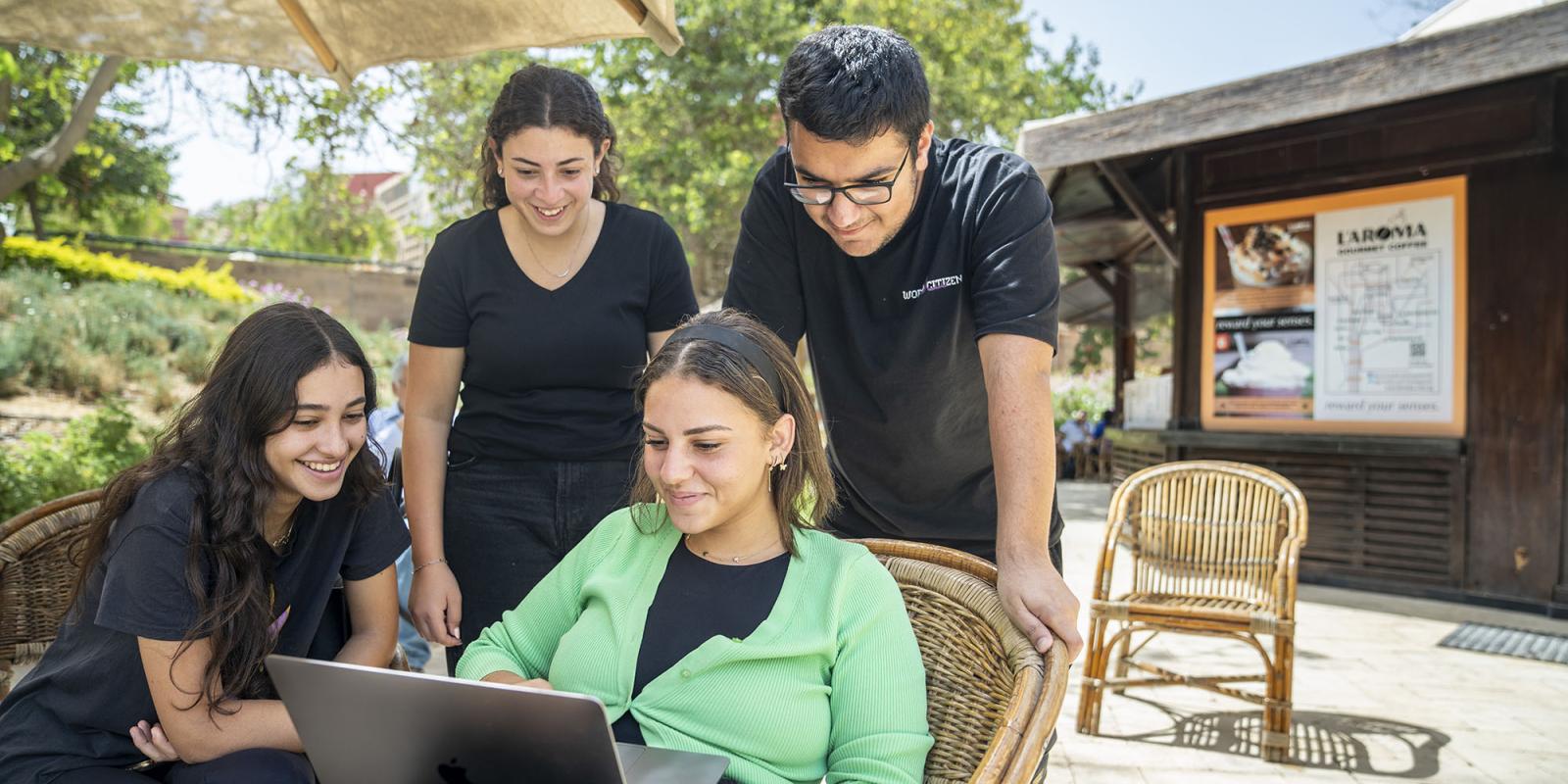 students in L'aroma around a computer