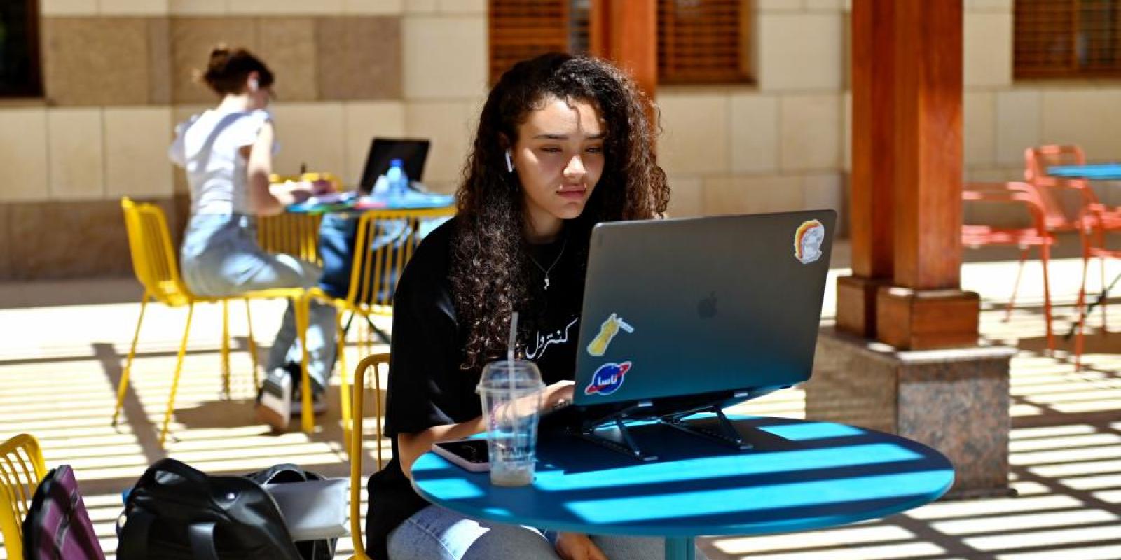 Girl sitting on her laptop outdoors