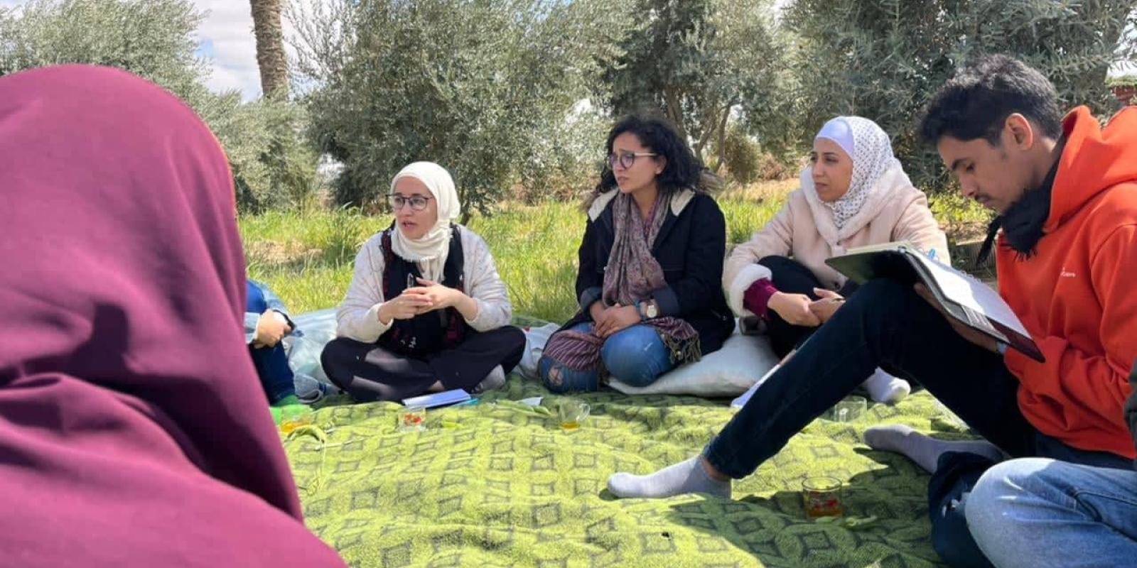 Group of girls and boys sitting outdoors on grass