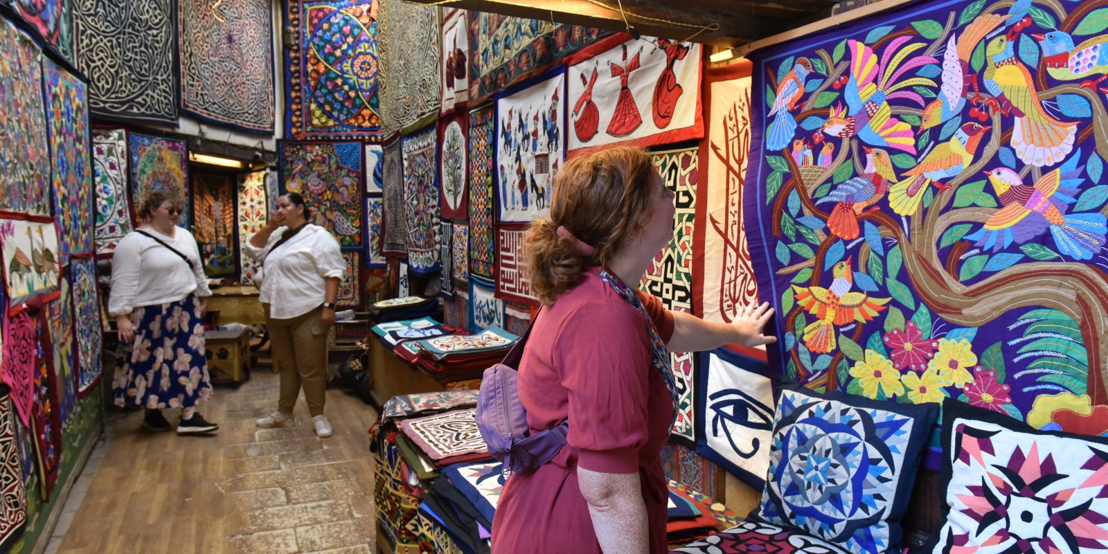 Woman in Cairo's tentmaker bazaar looking at a colorful piece of patchwork