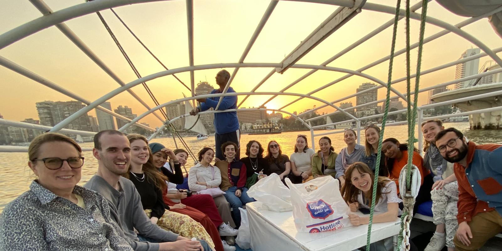 people on a felucca boat on the Nile, smiling as the sun sets behind them