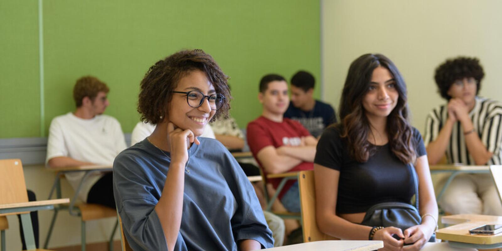 students sit in a classroom at AUC in front of a green wall