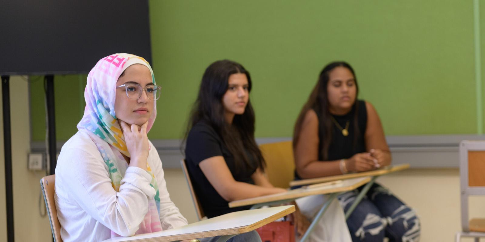 Three girls sitting in class