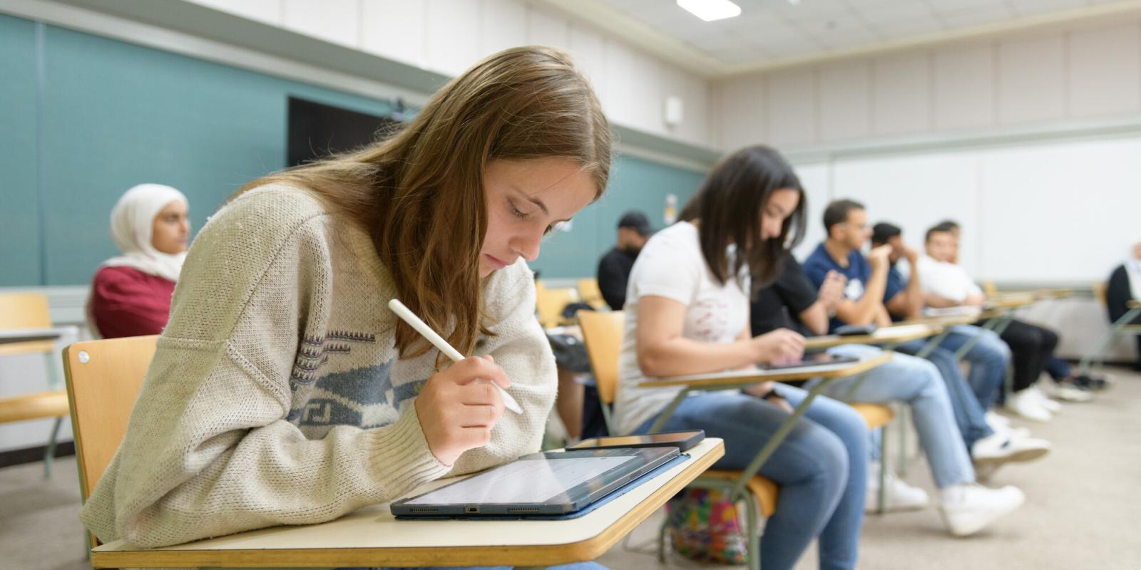 Students sitting in class writing