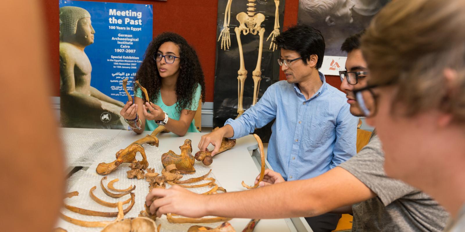 People sitting in front of a table that has human bones on it