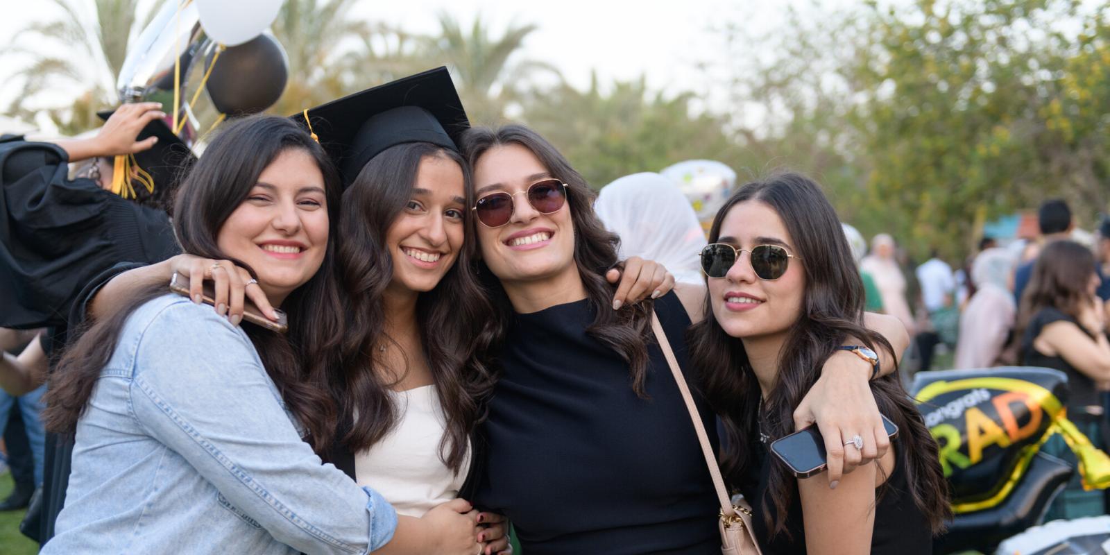 A group of girls smiling and one of the girls wearing a graduation cap