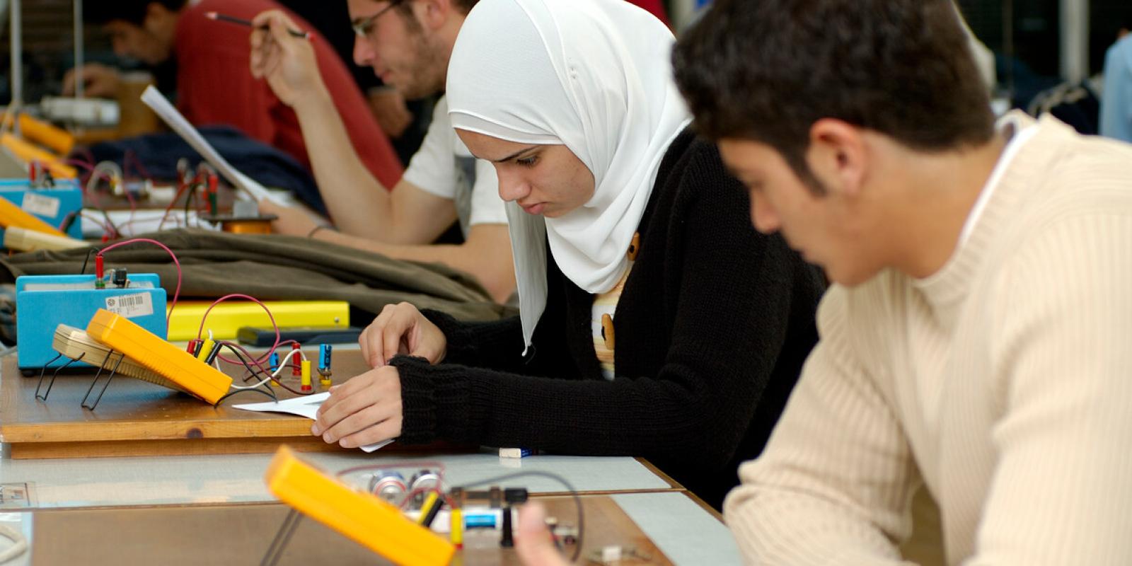 Students sit in a classroom working on brightly colored electronics