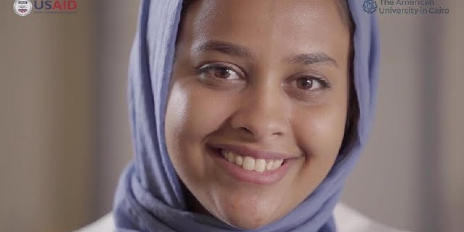 A girl smiling, text reads "The American University in Cairo and USAID"