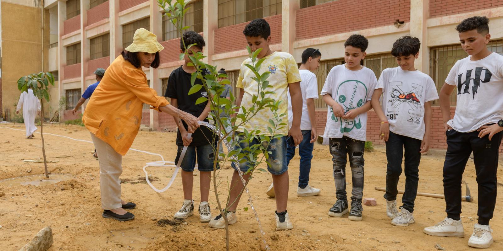 Professor plants trees with public school students in their playground