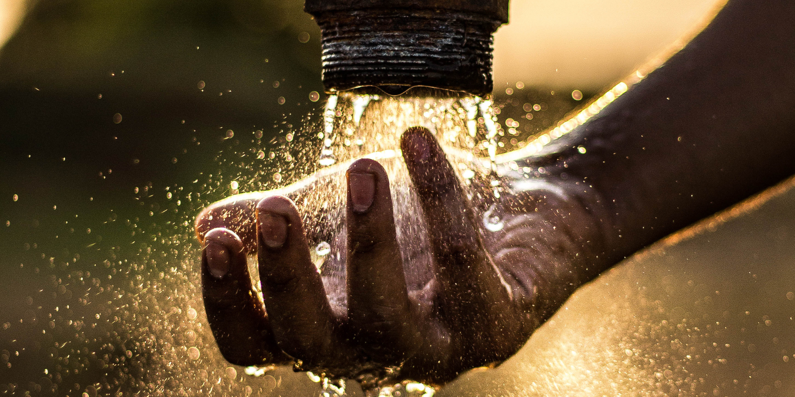 Hand touching water from a faucet