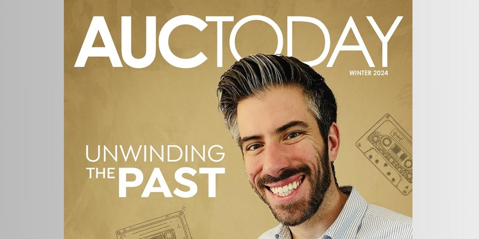 A man is smiling and holding a book, text reads "AUCToday. Unwinding the Past"