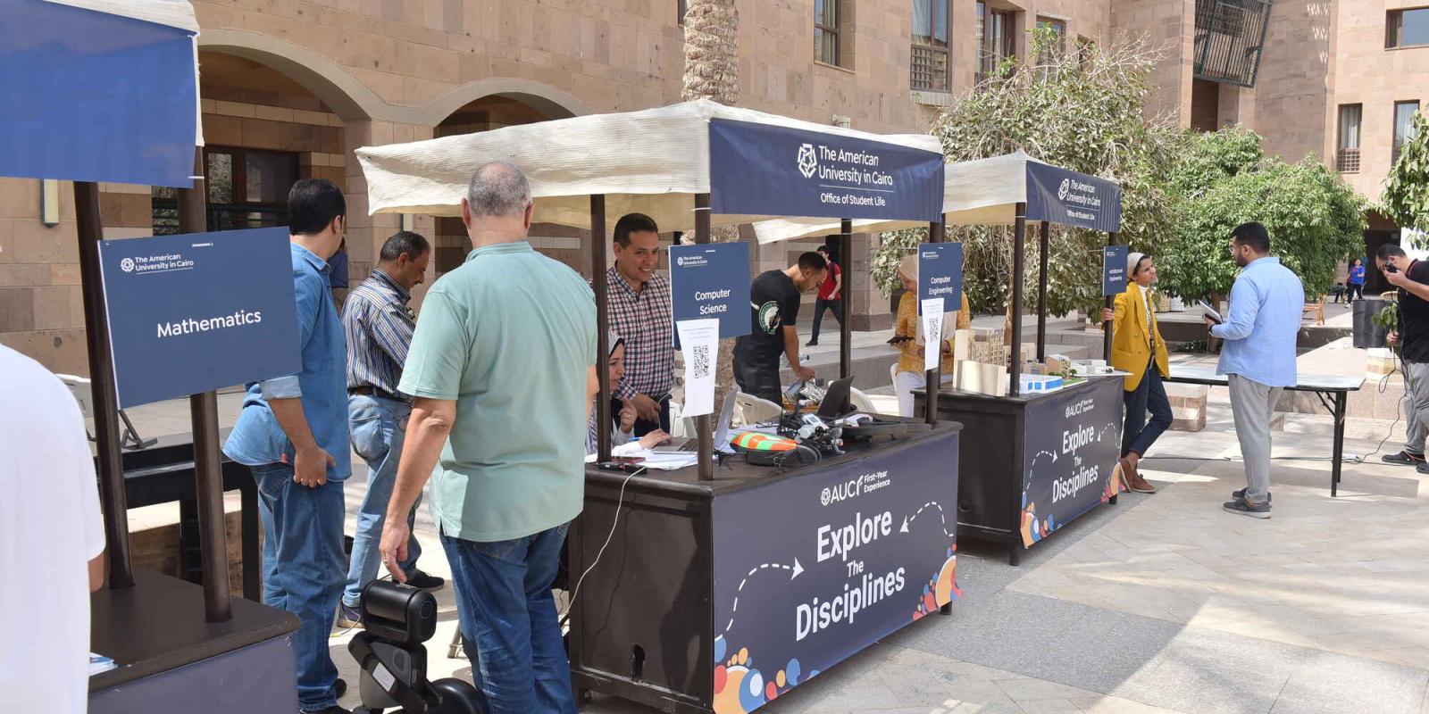 professors standing at booths of explore the disciplines fair