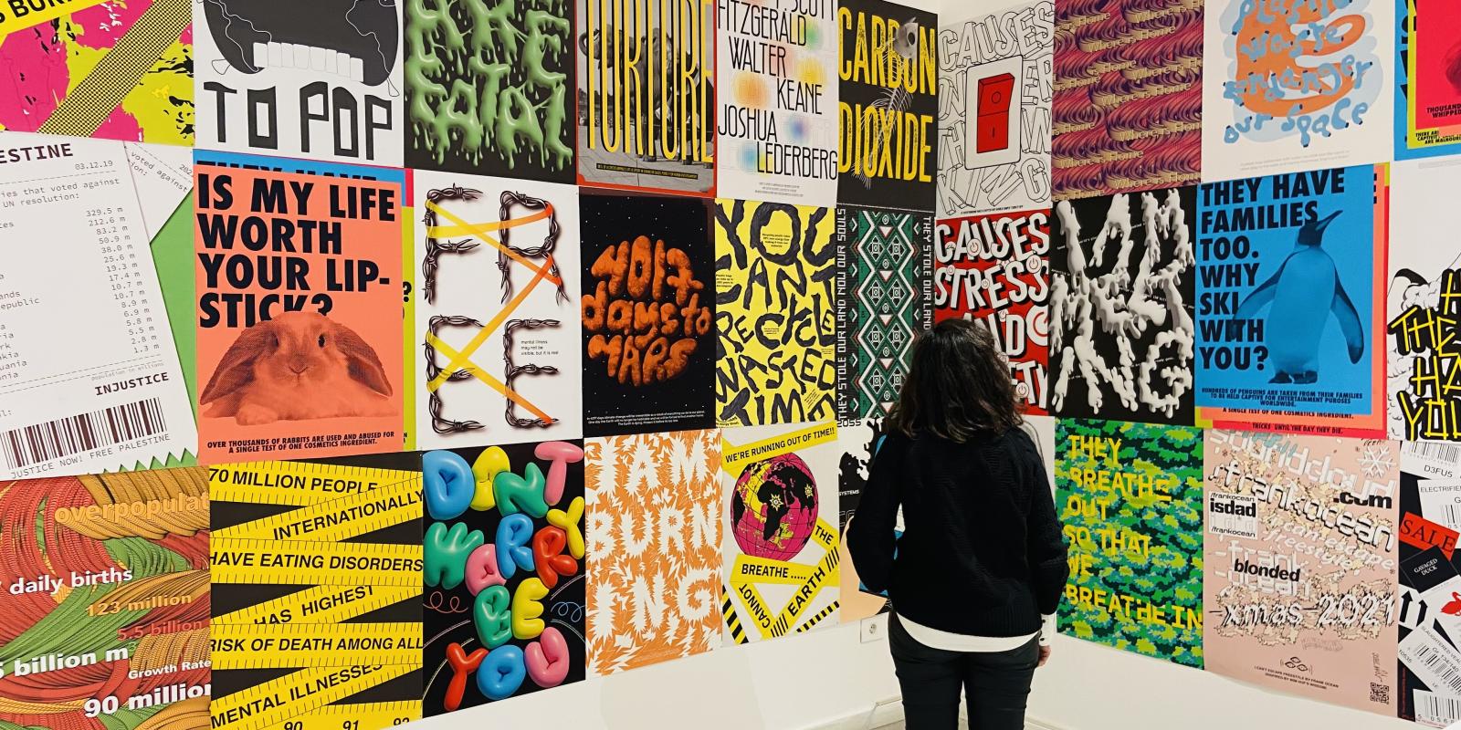 Person stands looking at a colorful wall filled with bright graphic art