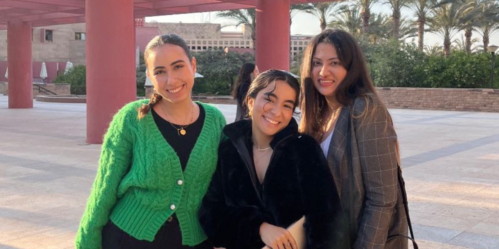 Three women smile on campus