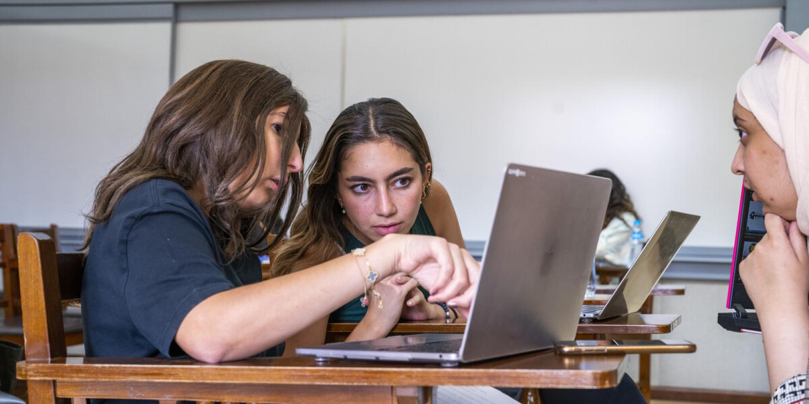 students in class pointing at laptop screen