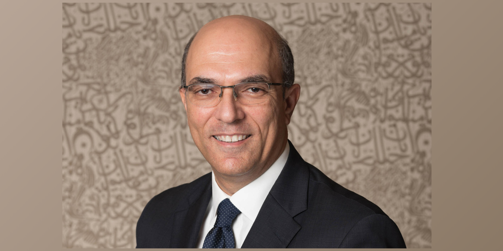 A man in a dark suit and black glasses