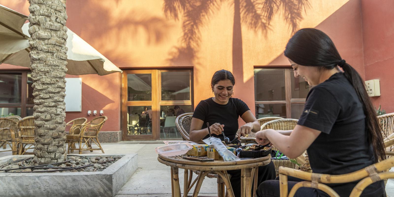 two girls sitting together having a nice snack at campus