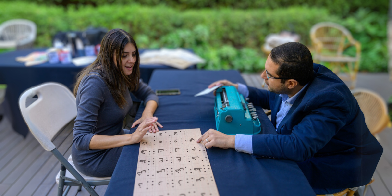 A man and a woman explore a wooden plank translating the Arabic alphabet into braille