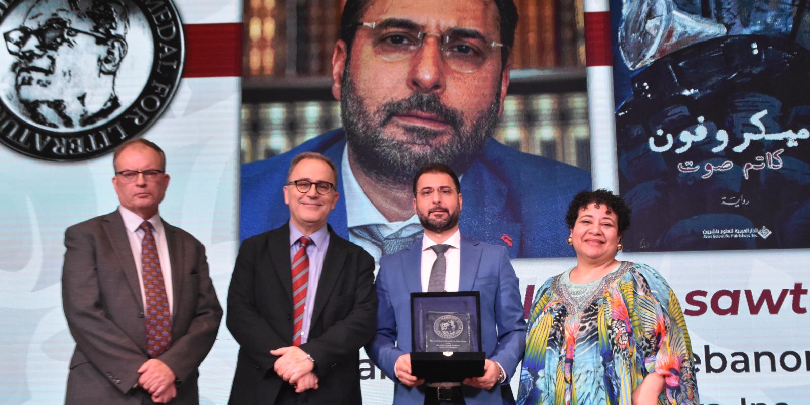 Group photo with the Naguib Mahfouz Medal winner holoding a trophy and standing with AUC President Ahmad Dalal, AUC Press Executive Director Thomas Willshire and Jury Chair Sarah Enany