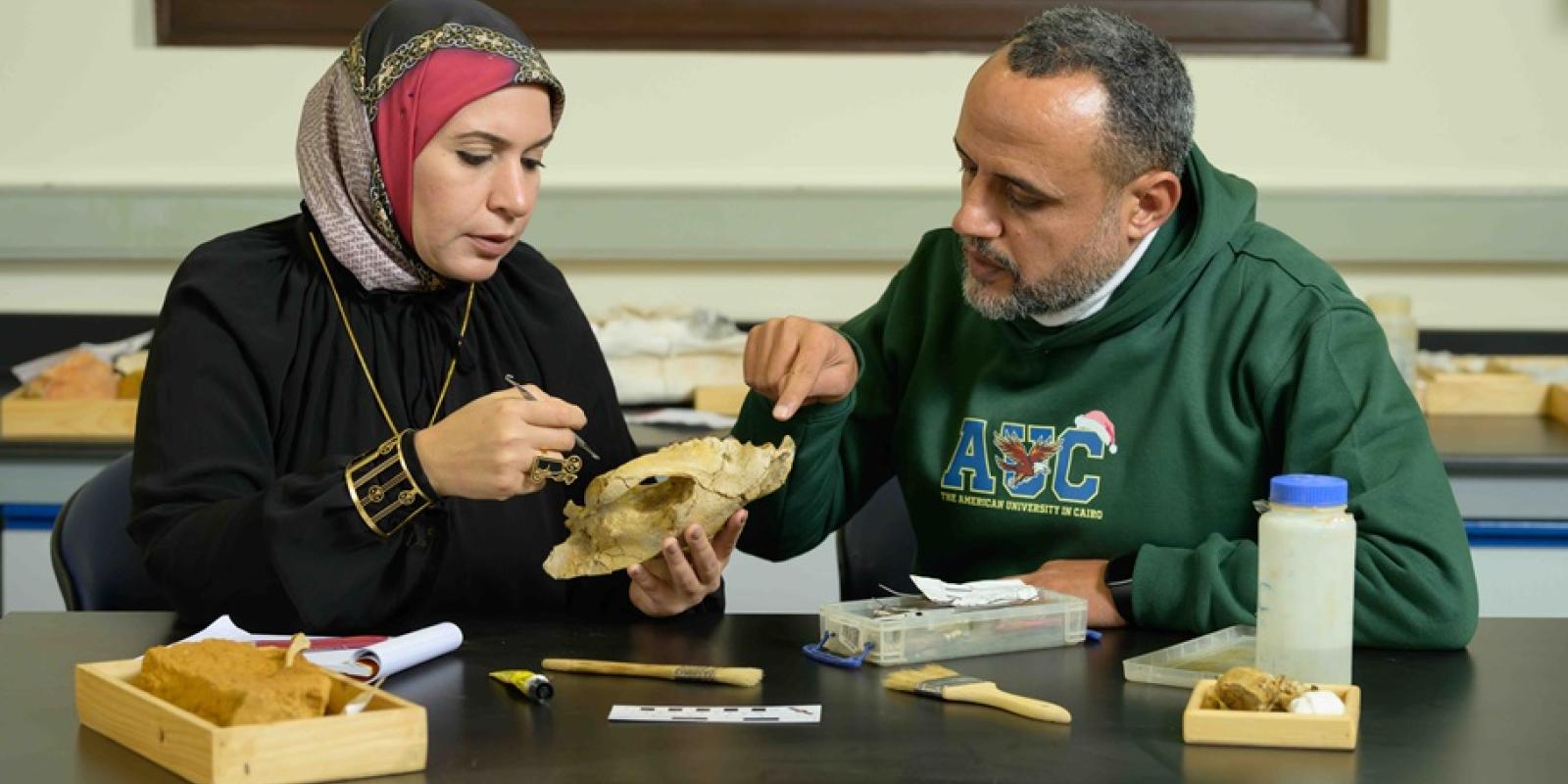 A woman and man holding a skull in a lab