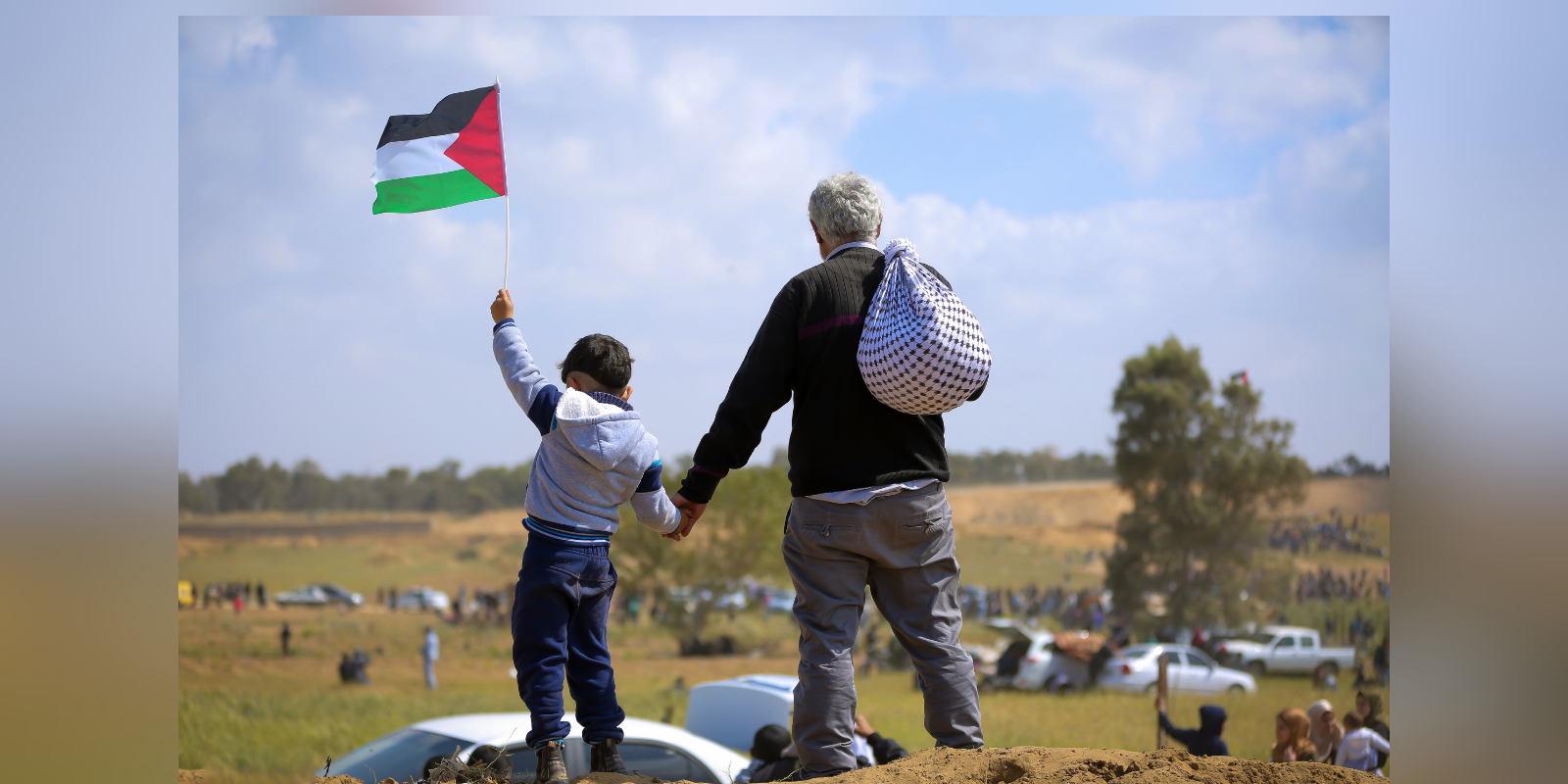 Boy holding Palestinian flag stands next to father