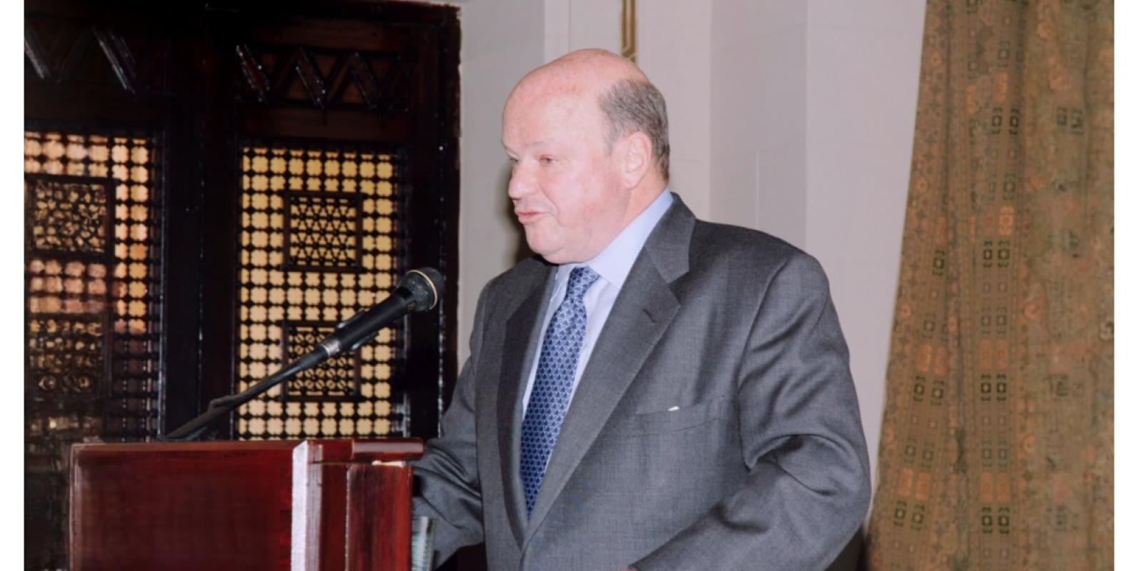 The late Ambassador Frank G. Wisner standing at an AUC podium and speaking into the microphone