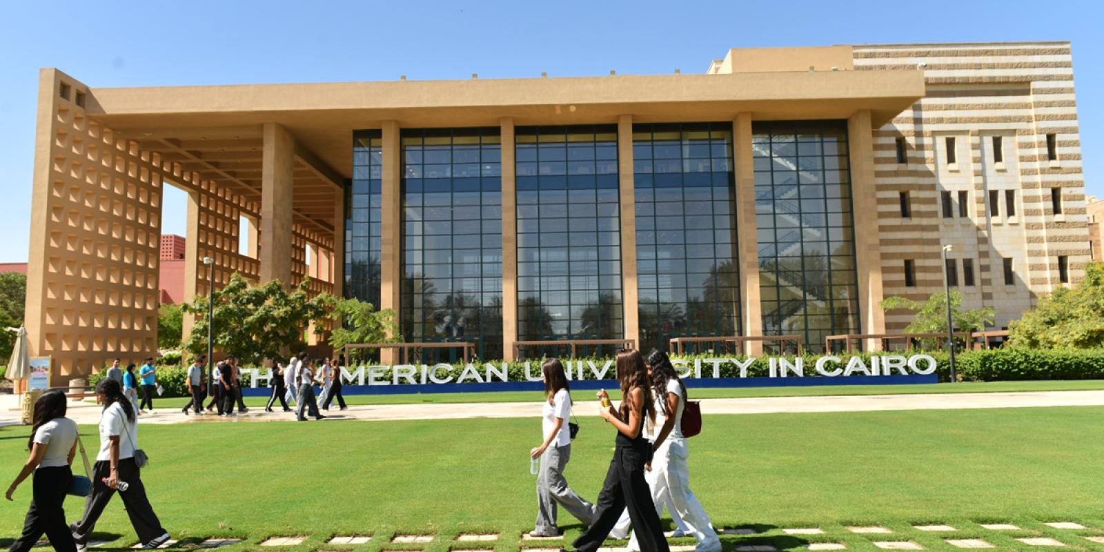 Students walking in front of a building. Text: The American University in Cairo