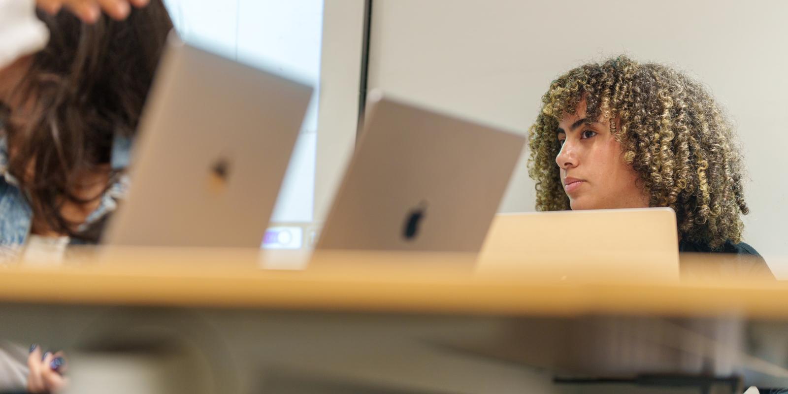 a student with short blond curly hair sitting in a classroom