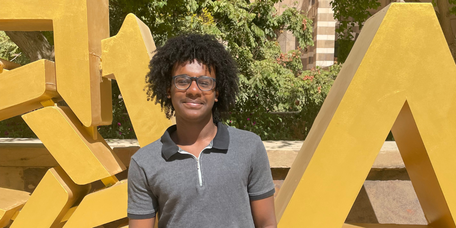 Ahmed Amara stands in front of a sign that reads AUC