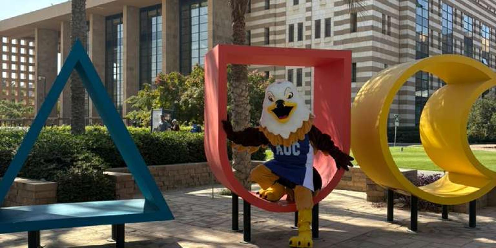 auc mascot sitting in the AUC monogram in the gardens