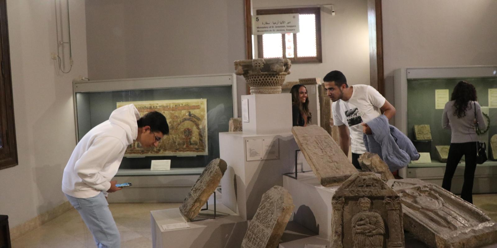 Students bending down and standing in front of Coptic monuments to examine them